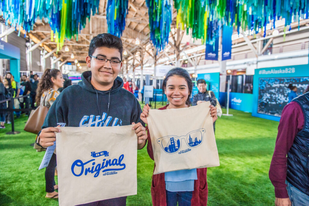Engaged experiential marketing event attendees holding branded promotional products to commemorate their unforgettable experience with Alaska Airlines