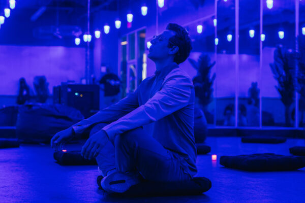 Man sitting in purple room practicing yoga