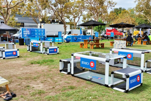 BMO fan zone activation with branded bench soccer tables, an "Official Bank of LAFC" game wall and picnic seating on the lawn outside BMO Stadium in Los Angeles, CA
