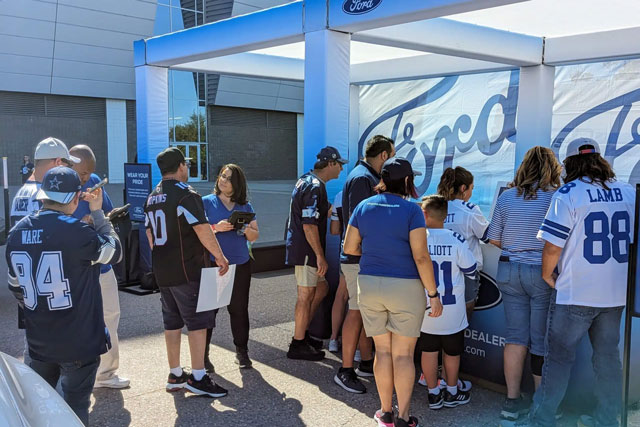 Fans engage with a Ford-branded booth during an outdoor automotive experiential marketing event, showcasing experiential marketing for automotive brands and strategic automotive event marketing.