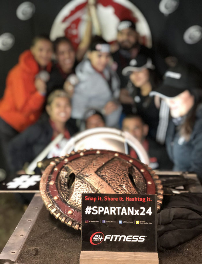 Spartan Race medal with people in background taking a group photo
